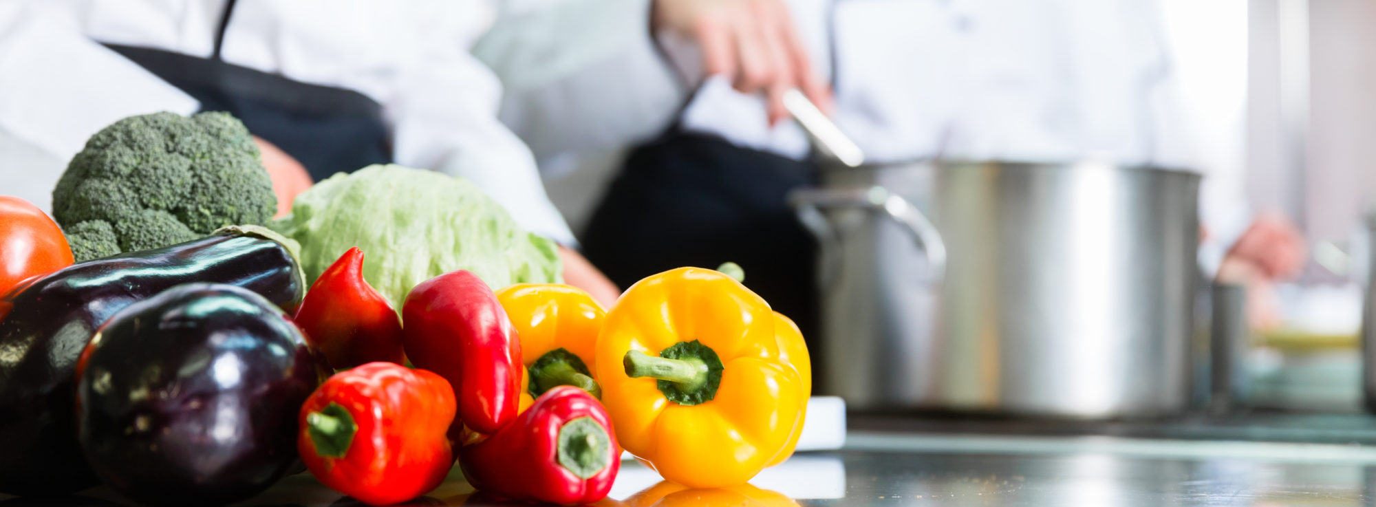 image of chefs preparing vegetables and stirring pot on a stove